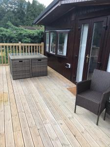a deck with a hot tub and a chair on a house at Daffodil Lodge in Builth Wells