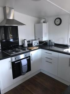 a kitchen with white cabinets and a stove top oven at Daffodil Lodge in Builth Wells