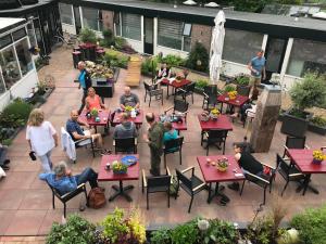 un groupe de personnes assises à des tables sur un patio dans l'établissement Pension Even Buiten, à Burgh-Haamstede