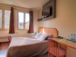 a bedroom with a bed and a desk with a computer at Logis Hôtel Restaurant Le Drakkar in Mende