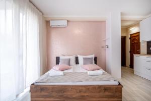 a bedroom with a large bed with pink pillows at MyFlat Siófok Beach Wellness Apartment in Siófok +21 photos