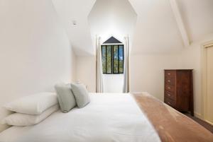 Un dormitorio con una gran cama blanca y una ventana en Briars Country Lodge en Bowral