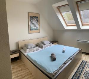 1 dormitorio con 1 cama grande con sábanas azules y ventanas en Tündérszikla Panzió en Pilisjászfalu