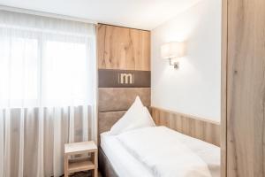 ein kleines Schlafzimmer mit einem Bett und einem Fenster in der Unterkunft Hotel Mondin in Ischgl