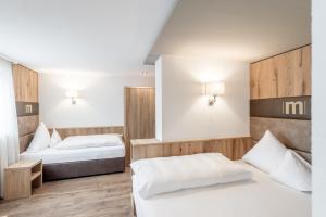 a bedroom with two beds and two lamps on the wall at Hotel Mondin in Ischgl