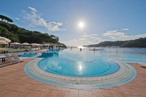 a large swimming pool next to a body of water at Hotel Cala di Mola in Porto Azzurro