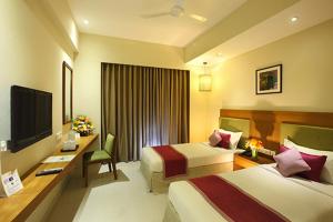 een hotelkamer met 2 bedden, een bureau en een televisie bij Jk Park Residency Perambra in Mennānyam