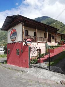 ein Gebäude mit einem Zaun davor in der Unterkunft Montano Camping & Hostel in Baños