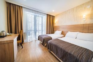 a hotel room with two beds and a desk at BM Plaza in Bakuriani