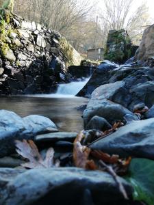 a river with a waterfall in the background with rocks at Casa Branca in Lousã +6 photos