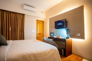 a hotel room with a television and a bed at Jatra Flagship Sylhet City Centre in Sylhet