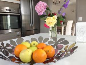a bowl of fruit on a table with a vase of flowers at Roissy Chambres in Roissy-en-France