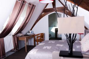 ein Schlafzimmer mit einem Bett und einem Tisch mit einer Lampe in der Unterkunft Manoir Desnachez in Taupont