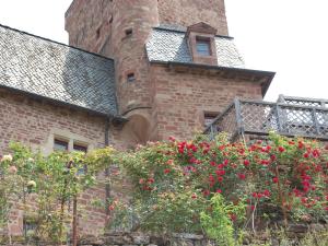 a brick building with red flowers in front of it at CHATEAU LA SERVAYRIE - Chambre d'hôtes in Marcillac-Vallon