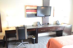 a desk with a computer and a tv on a wall at Holiday Inn Houston West - Westway Park, an IHG Hotel in Houston