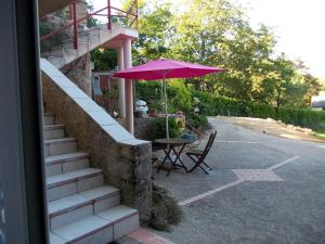 un tavolo con ombrello rosa accanto a un tavolo con di Au Soleil Levant Homestay a Sarlat-la-Canéda