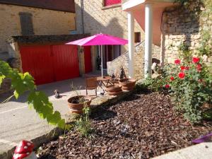 eine Terrasse mit einem rosa Regenschirm und einigen Pflanzen in der Unterkunft Au Soleil Levant Homestay in Sarlat-la-Canéda