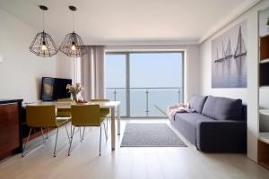 salon ze stołem i kanapą oraz jadalnią w obiekcie Apartamenty Na Klifie w mieście Ustronie Morskie
