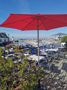 um guarda-sol vermelho sentado num deque com mesas e cadeiras em Hôtel Port Haliguen em Quiberon