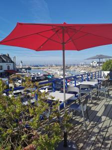 a red umbrella sitting on a deck with tables and chairs at Hôtel Port Haliguen in Quiberon