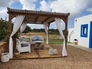 Villa Marta Formentera في سانت فيران دي سيس روكيه: شرفة خشبية مع أريكة وكراسي على الفناء