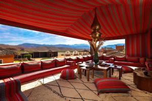 eine Terrasse mit roten Sofas, einem Tisch und Stühlen in der Unterkunft Kalyptus Luxury Camp in Lalla Takerkoust