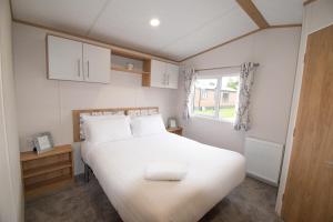 a bedroom with a white bed and a window at Yorkshire Lodge with Hot Tub in York +17 photos