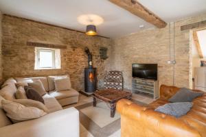 a living room with leather furniture and a tv at Middle Barn in Dyrham