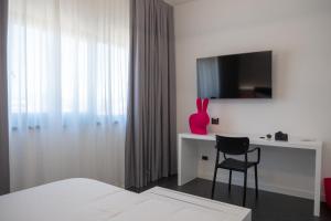 a white bedroom with a desk and a chair at My Suite Hotel in LʼAquila