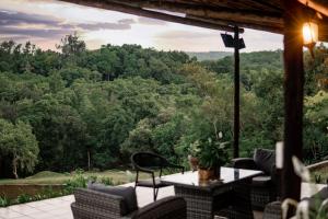eine Terrasse mit einem Tisch, Stühlen und Bäumen in der Unterkunft Bushbaby Valley Lodge in Hazyview