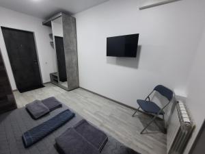キーウにあるПосуточно мини-студия метро Минская Киевの椅子と薄型テレビ付きの客室です。