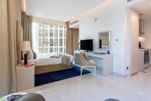 a bedroom with a bed and a desk and a television at The Smart Concierge - The Vogue in Dubai
