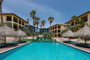 ウィレムスタッドにあるKunuku Resort All Inclusive Curacao, Trademark by Wyndhamのリゾートの前にあるスイミングプール(椅子、パラソル付)