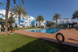 een zwembad met palmbomen en gebouwen op de achtergrond bij Cala Blanca, bajo, 2 dormitorios, by Bookindenia in Denia