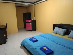 a bedroom with two beds with blue sheets and a refrigerator at E2S Place in Nakhon Nayok