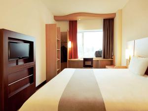 a hotel room with a large bed and a television at ibis London Luton Airport in Luton
