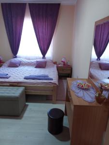 a bedroom with two beds with purple curtains at Valja Mare Moma in Golubac