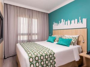 a bed room with a white bedspread and a blue comforter at Mercure Sao Paulo Pinheiros in São Paulo