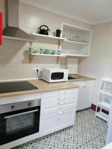 eine Küche mit weißen Schränken und einer Mikrowelle auf der Theke in der Unterkunft Aliciamar E by Casas de Setúbal in Setúbal