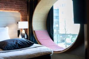 una camera da letto con specchio, letto e finestra di Solo Sokos Hotel Lahden Seurahuone a Lahti