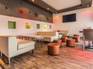 a waiting room with tables and chairs and a flat screen tv at ibis Oran les Falaises in Oran