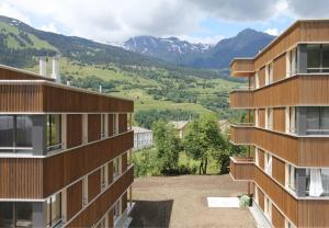 a view of two buildings with mountains in the background at Ual da Flex (Ava 4) in Savognin
