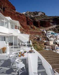 a balcony with white chairs and a view of a hill at Amoudi Villas in Oia