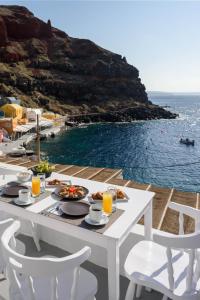 a white table with food and a view of the ocean at Amoudi Villas in Oia