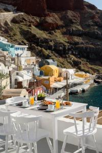 a white table and chairs with a view of a harbor at Amoudi Villas in Oia