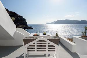 a white table and chairs on a balcony overlooking the ocean at Amoudi Villas in Oia