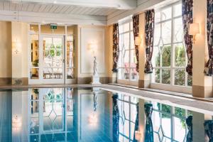 a swimming pool in a hotel lobby with windows at Relais & Châteaux Hotel Schwarzmatt in Badenweiler