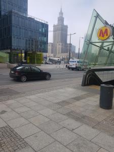 un coche negro conduciendo por una calle de la ciudad con un edificio en Studio Centrum en Varsovia