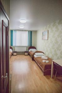イジェフスクにあるHotel Mirのベッド2台とテーブルが備わる客室です。