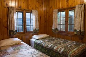 Riverside Point Resort في Park Rapids: سريرين في غرفة بجدران خشبية ونوافذ